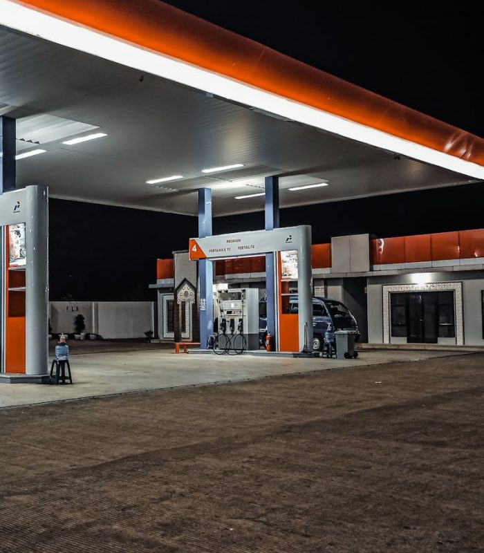 A contemporary gas station illuminated at night, highlighting pump stations and canopy.
